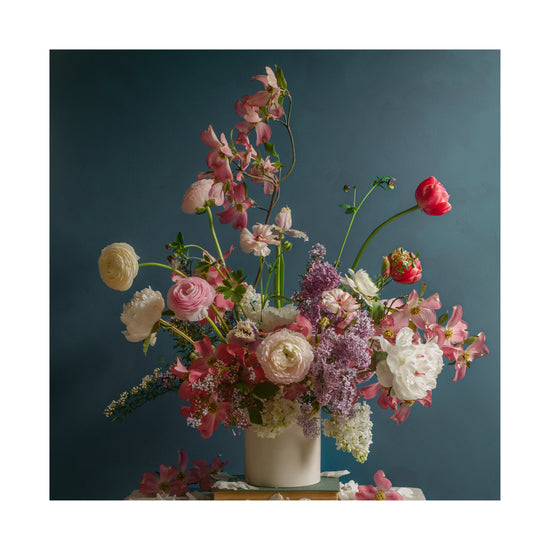 The Spring Ballet Poster showcases a vibrant flower arrangement in a white vase against a teal background, with pink, red, white, and purple roses, tulips, and lilacs. Scattered petals add an elegant touch.