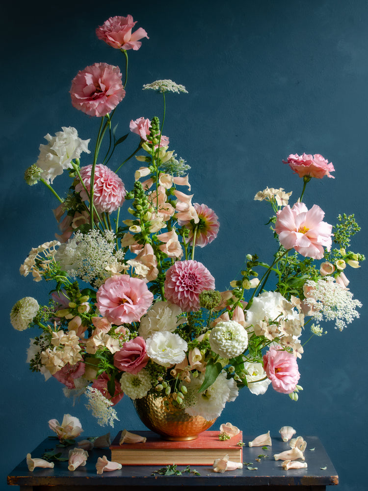 The Midsummer Poster features a lush bouquet of pink, white, and blush flowers such as roses, peonies, and wildflowers in a gold vase set against a dark teal background with scattered petals below.