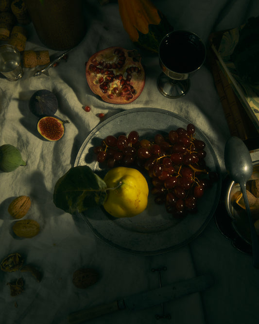 Still life photograph of a sheet with different fruits and objects on it.