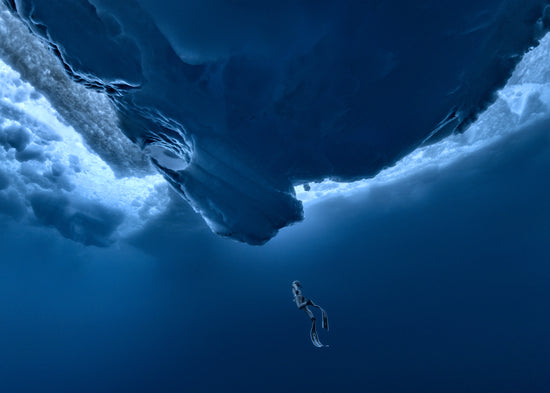 Lonely free-diver swimming towards a surface covered in ice.