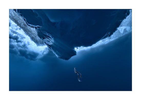 Lonely free-diver swimming towards a surface covered in ice.