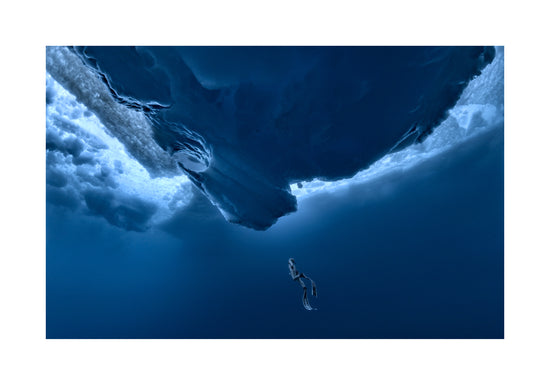 Lonely free-diver swimming towards a surface covered in ice.