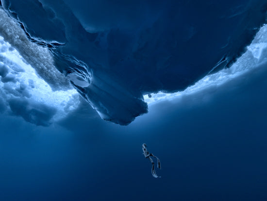Lonely free-diver swimming towards a surface covered in ice.