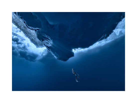 Lonely free-diver swimming towards a surface covered in ice.