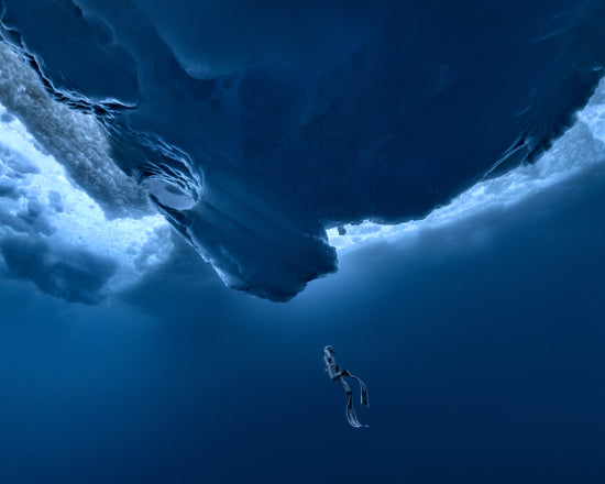 Lonely free-diver swimming towards a surface covered in ice.