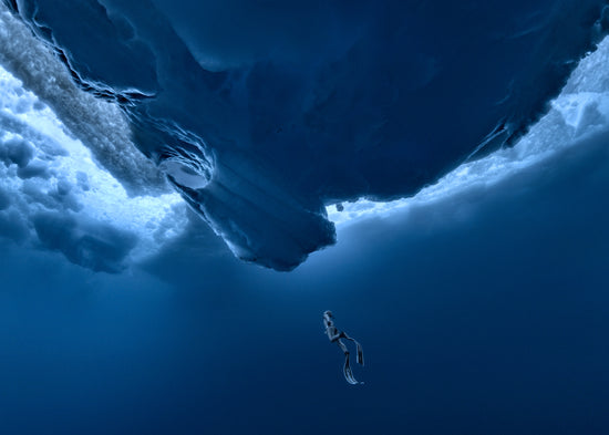 Lonely free-diver swimming towards a surface covered in ice.