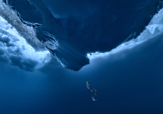 Lonely free-diver swimming towards a surface covered in ice.