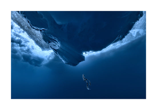 Lonely free-diver swimming towards a surface covered in ice.