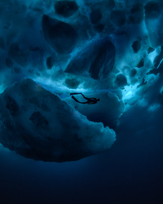 Diver swimming underneath ice bergs.