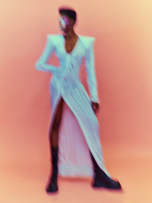 A blurry poster of a woman in a white dress in front of a peach pink background.