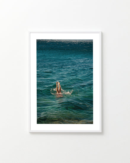 Legs of a person diving into the sea with their torso under the water’s surface.