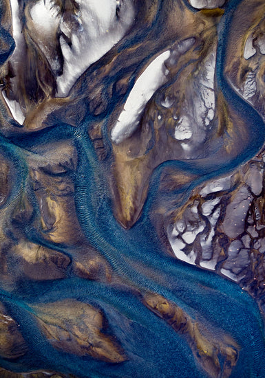 Blue streams rippling down a mountain path covered in snow.