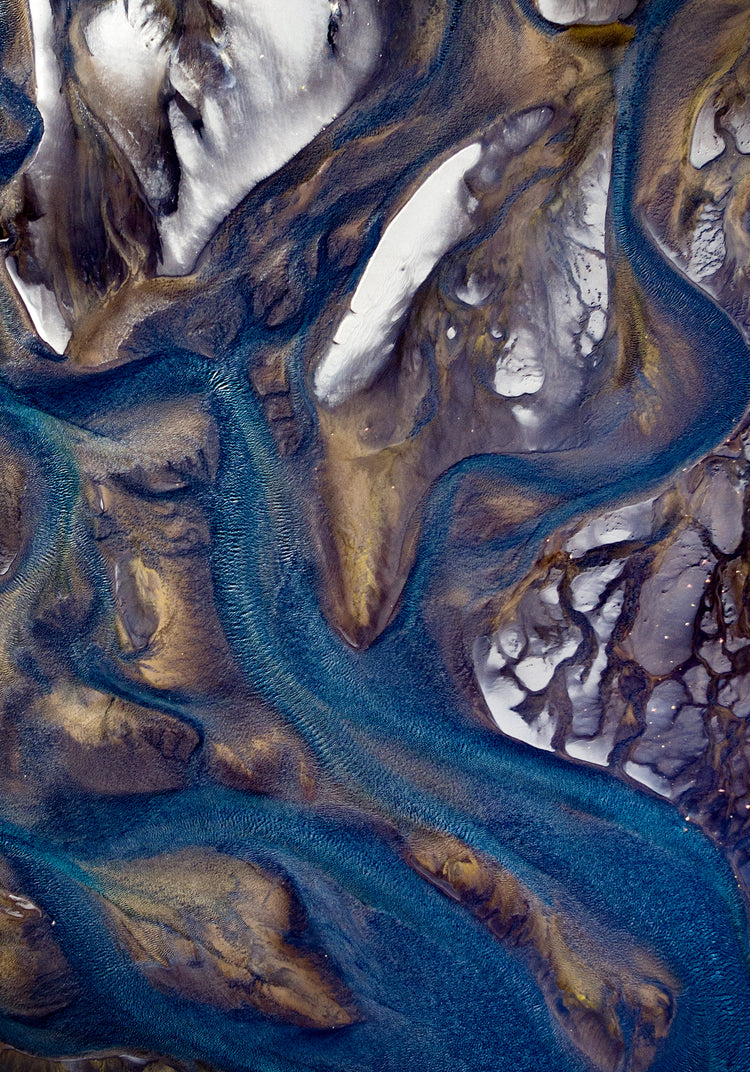 Blue streams rippling down a mountain path covered in snow.