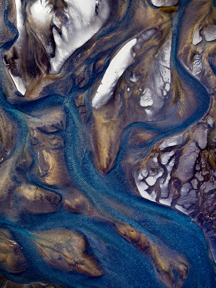 Blue streams rippling down a mountain path covered in snow.