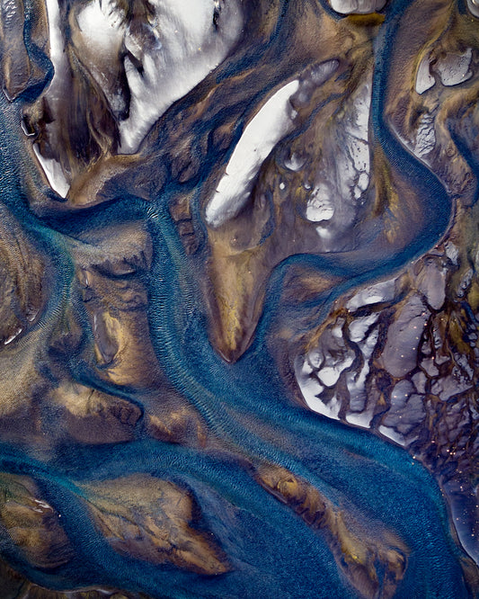 Blue streams rippling down a mountain path covered in snow.