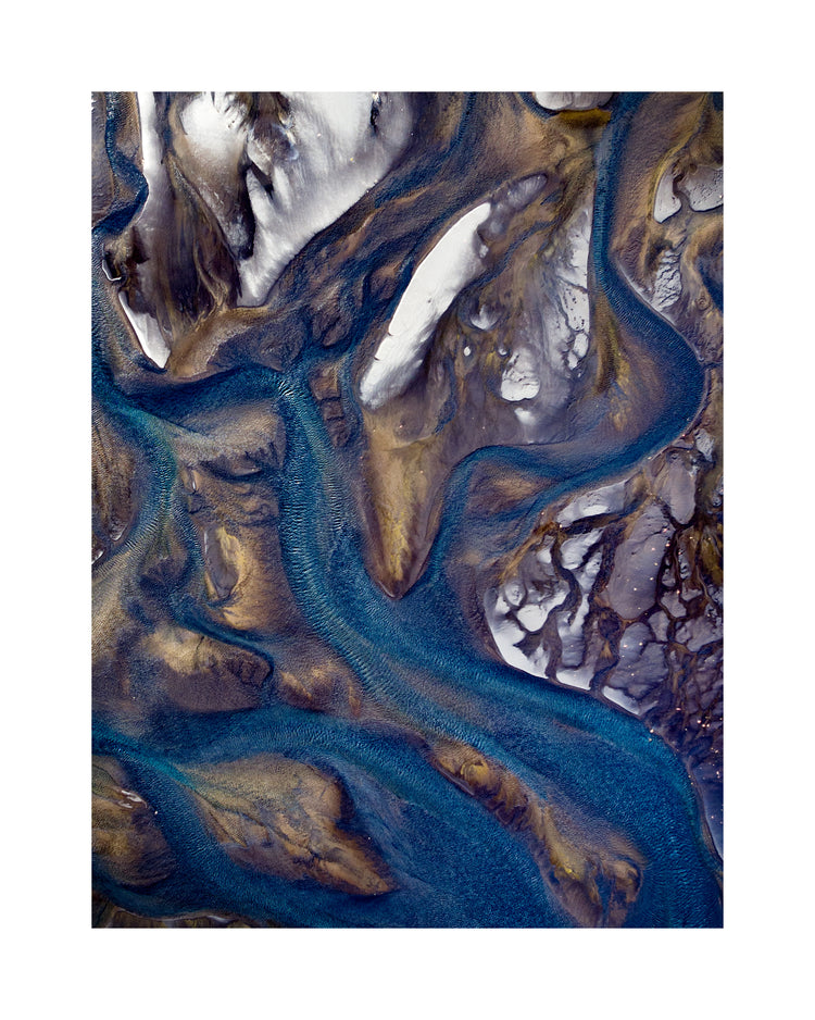 Blue streams rippling down a mountain path covered in snow.
