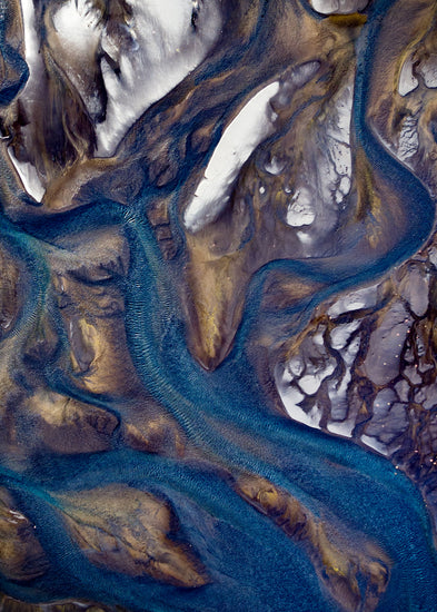Blue streams rippling down a mountain path covered in snow.