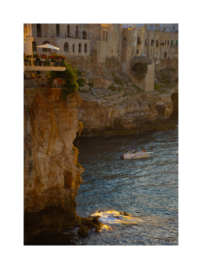 Sun setting over an Italian lake surrounded by houses on high cliffs.
