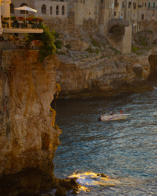 Sun setting over an Italian lake surrounded by houses on high cliffs.
