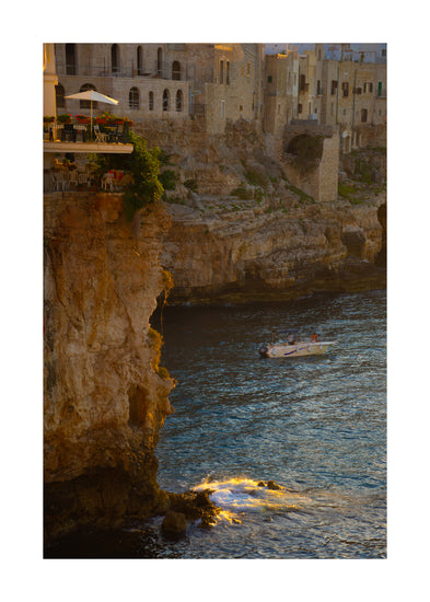 Sun setting over an Italian lake surrounded by houses on high cliffs.