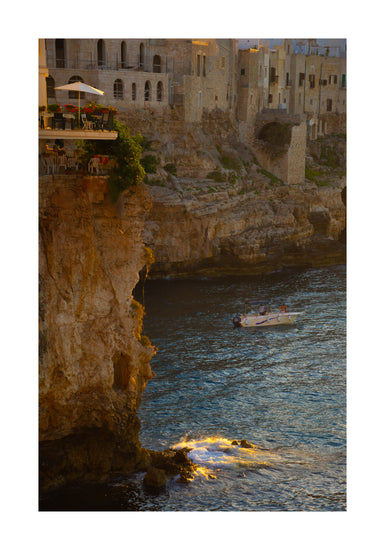 Sun setting over an Italian lake surrounded by houses on high cliffs.