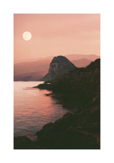 Full moon shining bright over the coastline set in a mountain scenery.