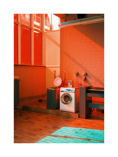 In a stylish laundromat-inspired room with orange and teal hues, a washing machine and sink rest against taupe walls. Sunlight streams through large windows, highlighting a mannequin torso with raised arms, capturing the artistry of the Laundry Day Poster by Delfina Carmona.