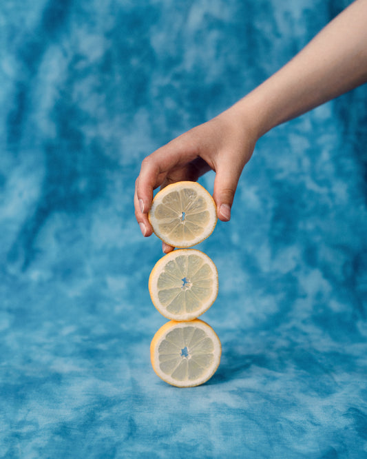 Three slices of freshly cut lemon on top of each other on a blue background.
