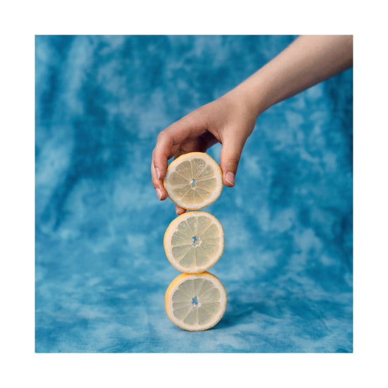 Three slices of freshly cut lemon on top of each other on a blue background.