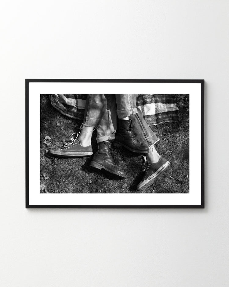 The entangled feet of a couple lying down on a picnic blanket.