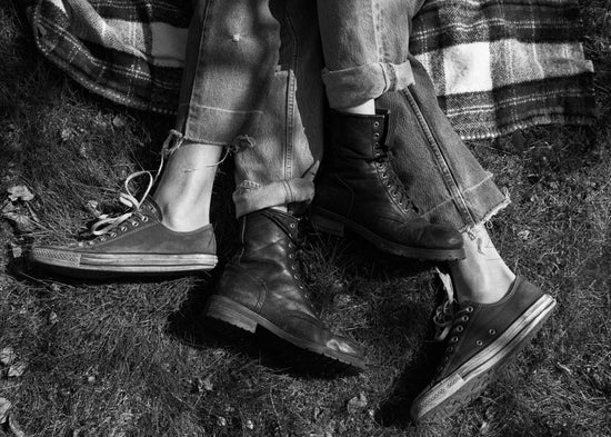 The entangled feet of a couple lying down on a picnic blanket.