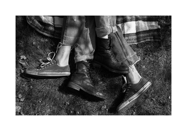 The entangled feet of a couple lying down on a picnic blanket.