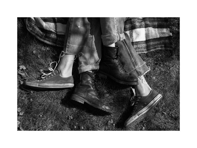 The entangled feet of a couple lying down on a picnic blanket.