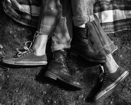 The entangled feet of a couple lying down on a picnic blanket.