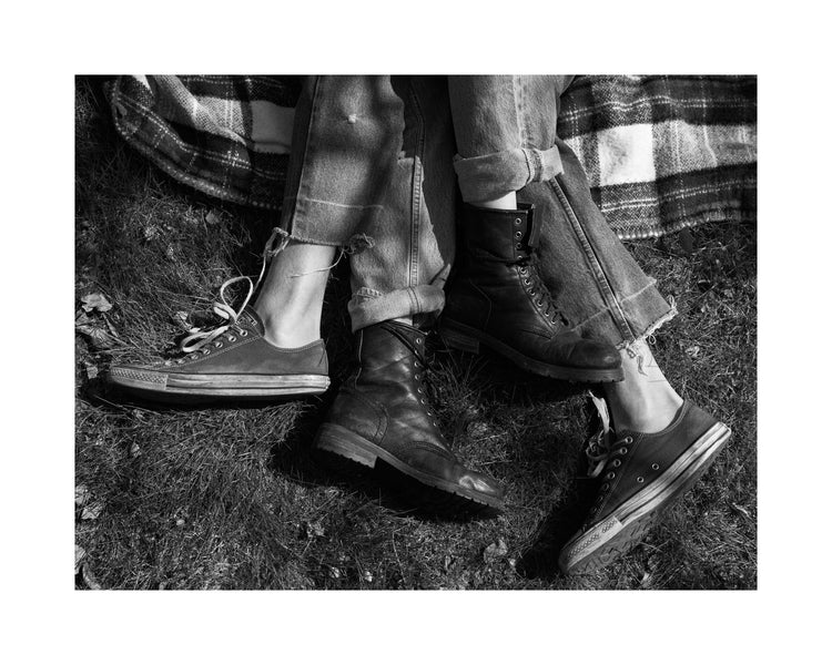 The entangled feet of a couple lying down on a picnic blanket.