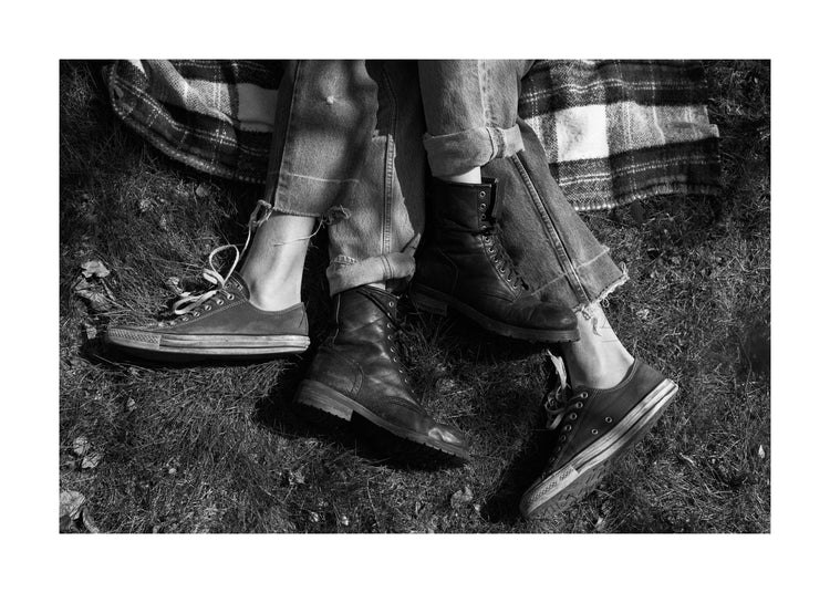The entangled feet of a couple lying down on a picnic blanket.