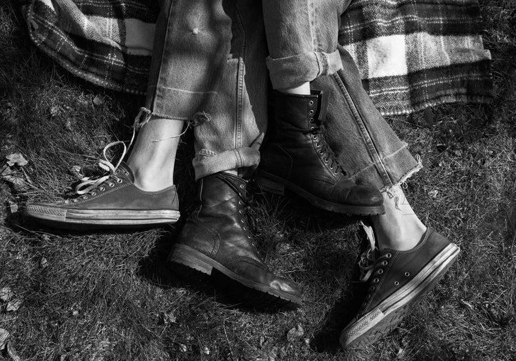 The entangled feet of a couple lying down on a picnic blanket.