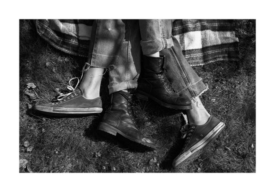 The entangled feet of a couple lying down on a picnic blanket.