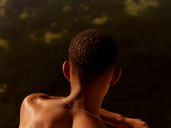 Smooth skinned man looking out over a blurry landscape.