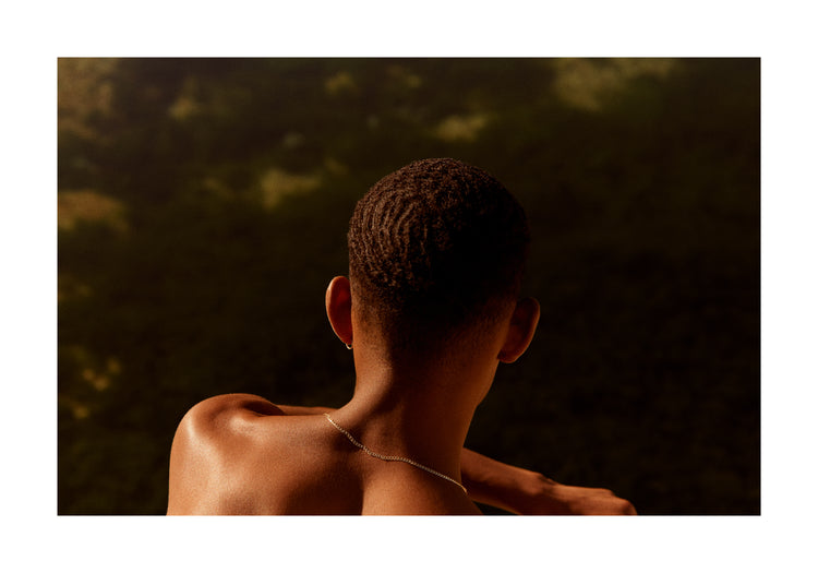 Smooth skinned man looking out over a blurry landscape.