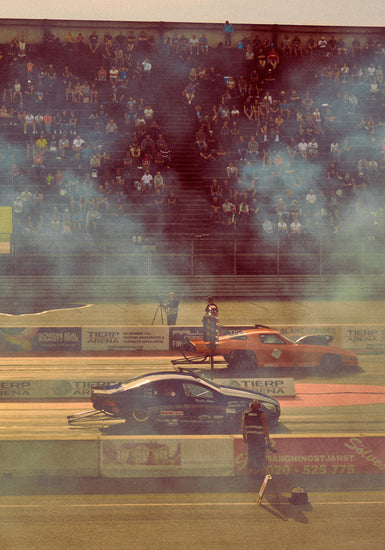 Cars lined up on a smokey race car track ready for take-off.