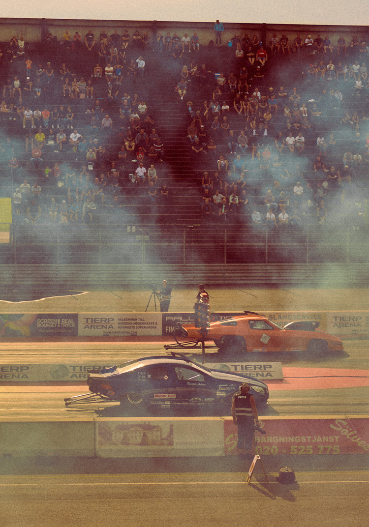Cars lined up on a smokey race car track ready for take-off.