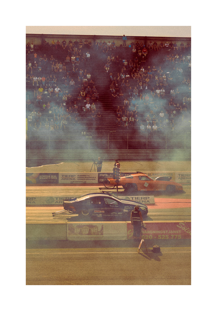 Cars lined up on a smokey race car track ready for take-off.