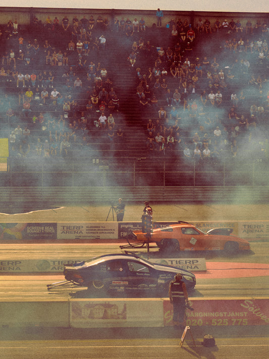 Cars lined up on a smokey race car track ready for take-off.