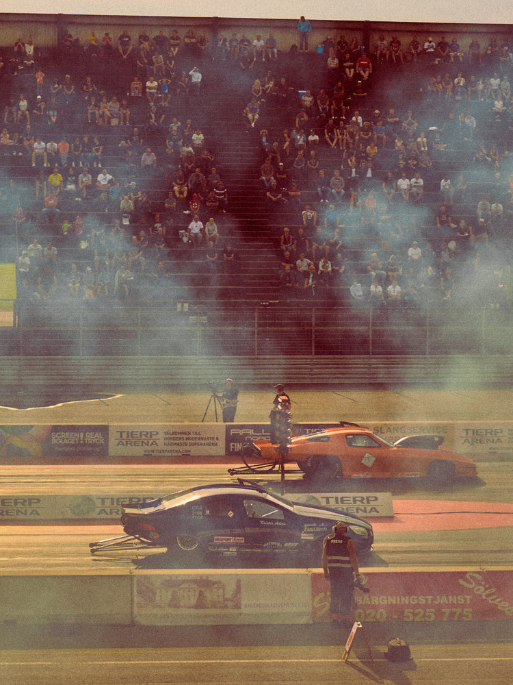 Cars lined up on a smokey race car track ready for take-off.