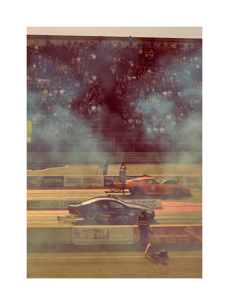 Cars lined up on a smokey race car track ready for take-off.