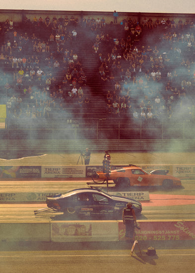 Cars lined up on a smokey race car track ready for take-off.