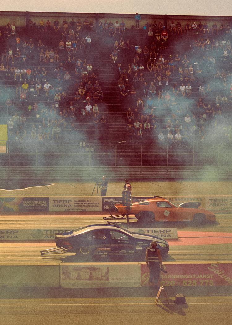 Cars lined up on a smokey race car track ready for take-off.