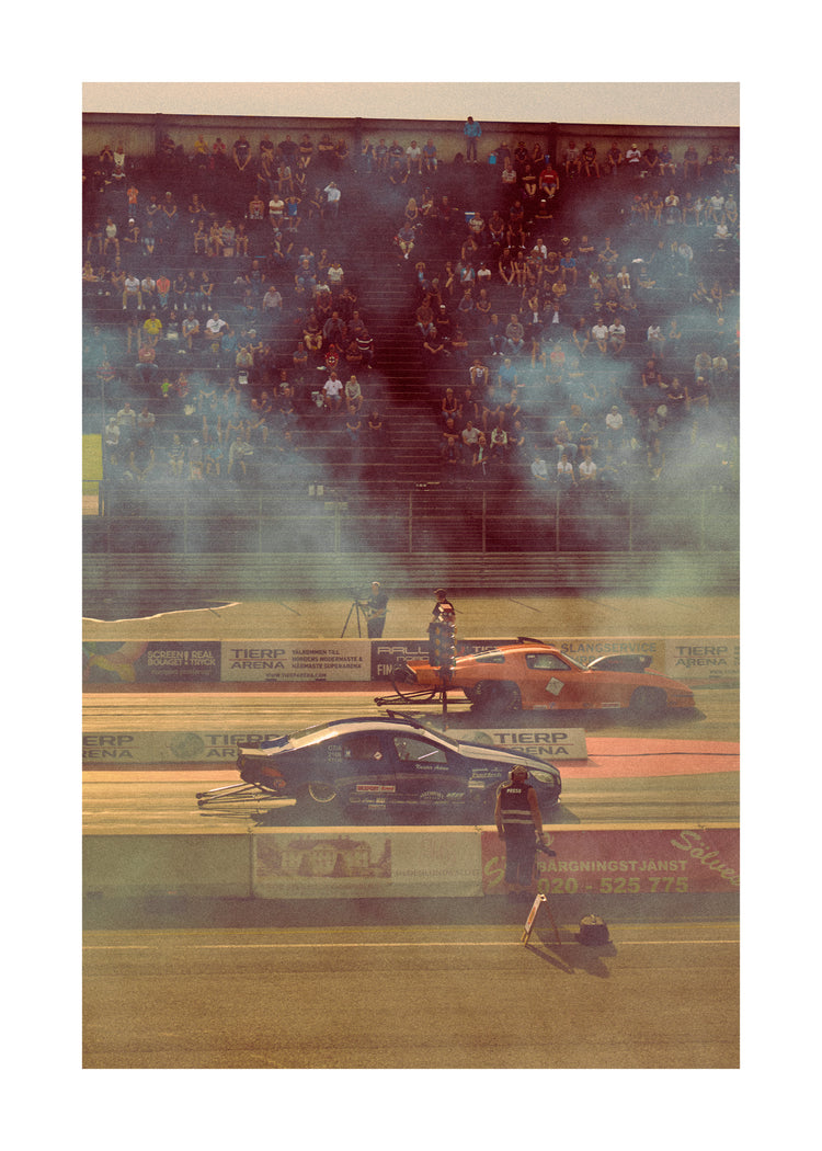 Cars lined up on a smokey race car track ready for take-off.