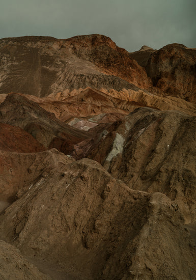 Rough mountain scenery with brown and orange cliffs captured from above.
